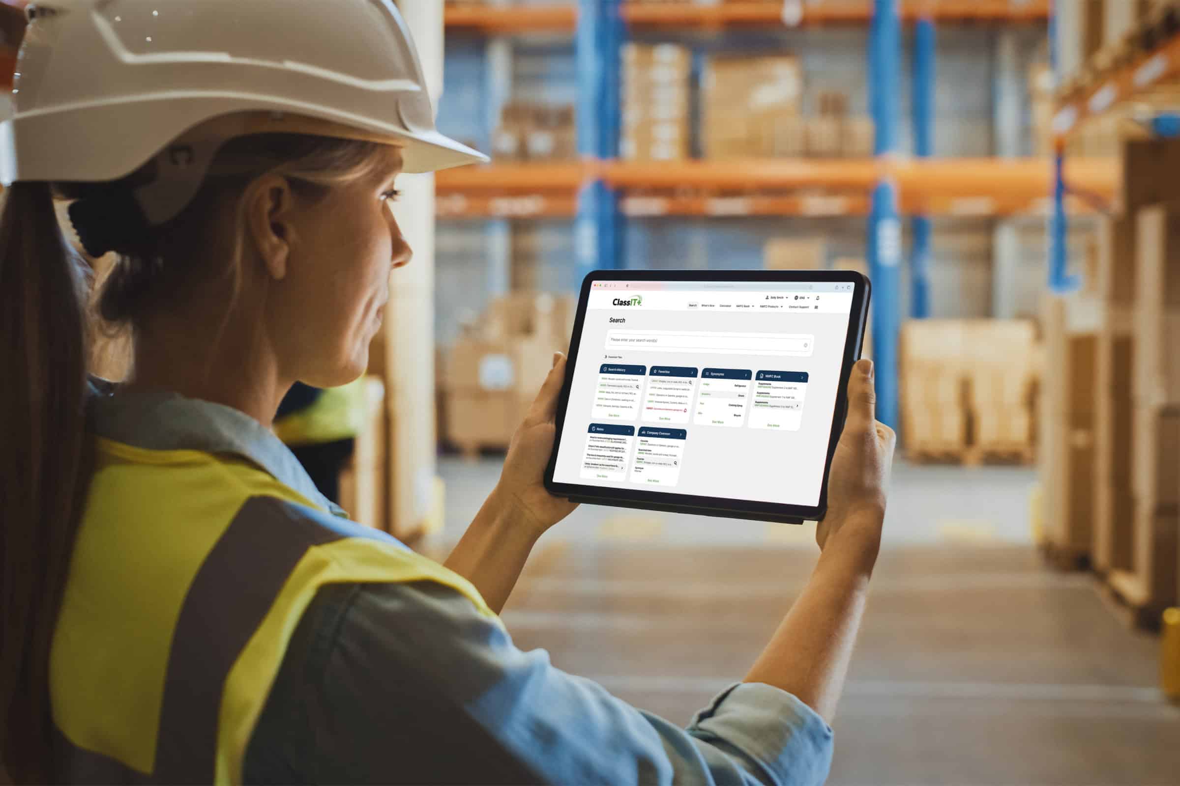 Warehouse worker monitoring freight management on tablet in a busy warehouse.