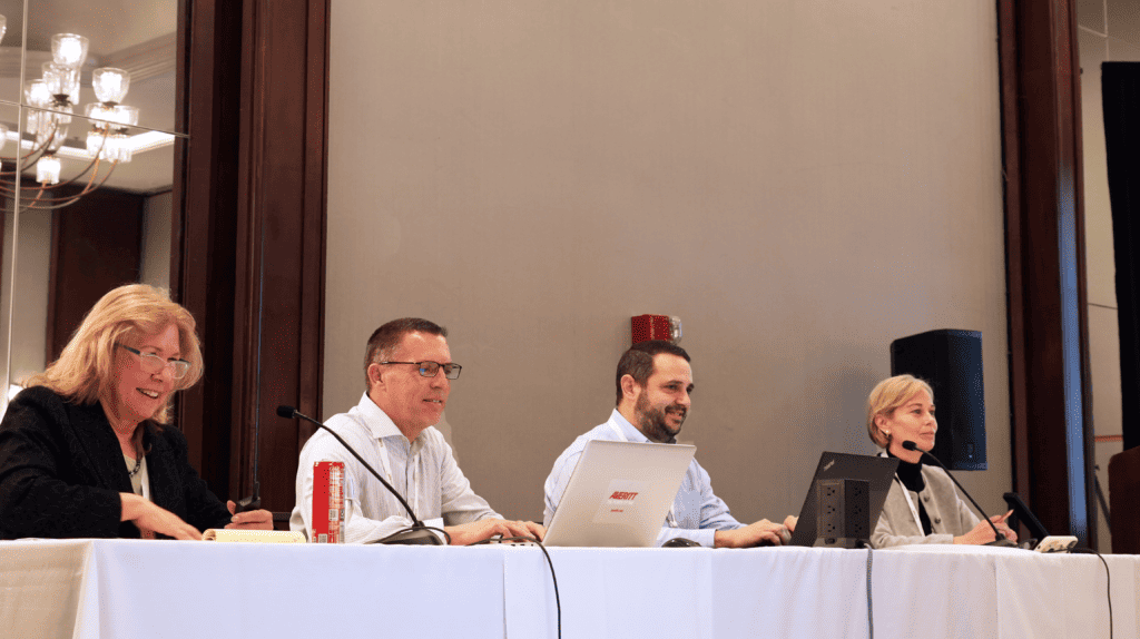 Kris McLennan speaking on a panel at an NMFTA conference with industry experts